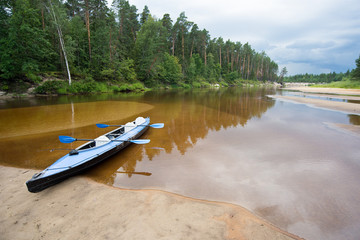 Kayak on the river in cloudy weather. The forest and the storm clouds in the background