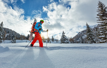 Snowboarder walking on snowshoes in powder snow.