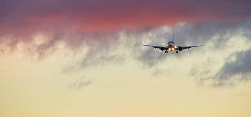 Commercial airplane jetliner landing in sunset