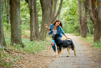 A young girl is walking with a German shepherd dog in the park.