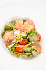 Baby spinach, dry sausage, matured cheese, roast tomatoes, thyme-balsamic vinaigrette salad on a white background