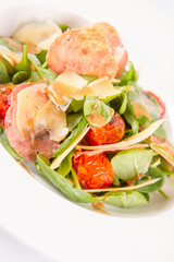 Baby spinach, dry sausage, matured cheese, roast tomatoes, thyme-balsamic vinaigrette salad on a white background