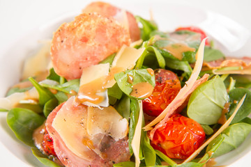 Baby spinach, dry sausage, matured cheese, roast tomatoes, thyme-balsamic vinaigrette salad on a white background