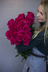 Beautiful young woman holding big bouquet of pink roses