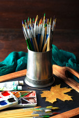 Paints for drawing and brush on a background in a composition