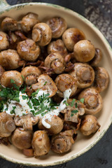 Above view of fried champignons and chanterelles with sour cream and parsley, close-up