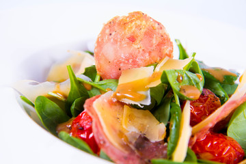 Baby spinach, dry sausage, matured cheese, roast tomatoes, thyme-balsamic vinaigrette salad on a white background