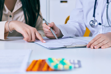 Patient signing medical contract. Female doctor explains how to fill medical form.
