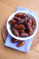 Bowl of dried dates on wooden background
