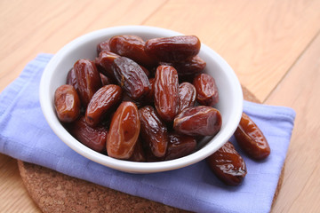 Bowl of dried dates on wooden background
