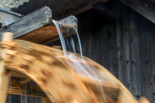The part of mill wheel rotates under a stream of water, open air museum. The wooden trough brings water to the water mill wheel.