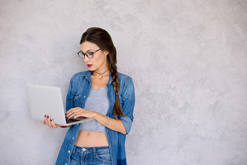 Woman in eyeglasses standing  focused to the laptop