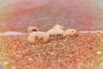 Beautyful sunlight with clean sea sand and the waves are blowing on the beach. Small rocks with inscription, near the water.