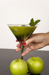 Green fruits and vegetables juiced in cocktail glass with a sprig of mint