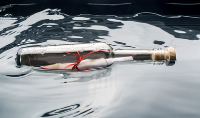 Flasche mit gerolltem Papier als Flaschenpost schwimmt im Wasser