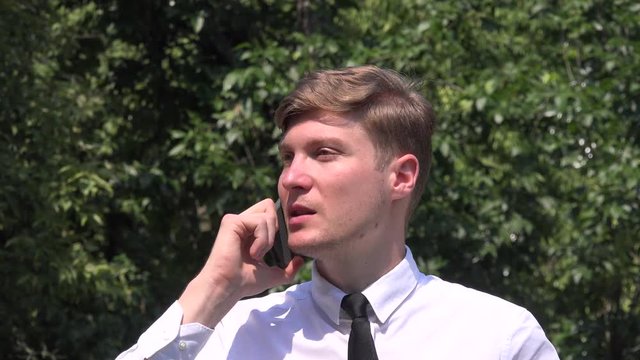 Handsome businessman in the park relaxing cell phone call conversation closeup