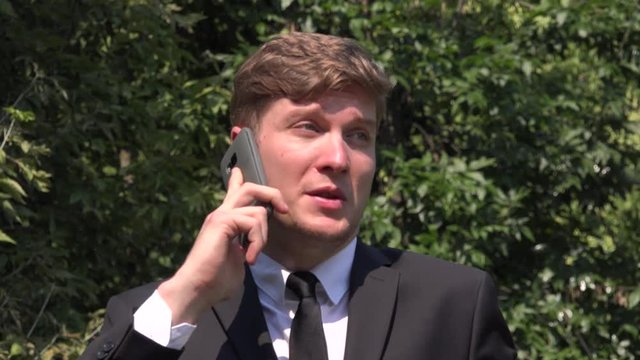 Handsome charming business man smile closeup talking on mobile phone in the park