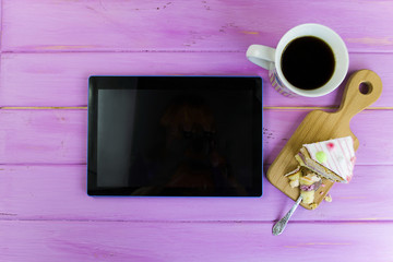 tablet and coffee cup on a pink wooden background