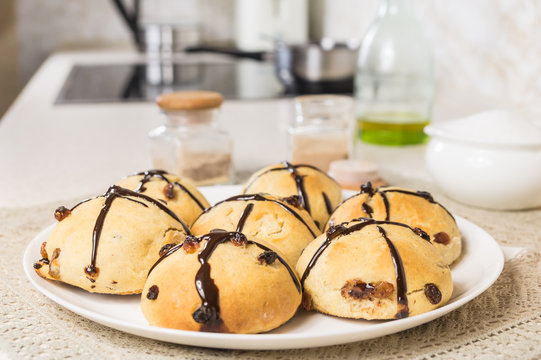 Close-up image of baked fresh cross buns. Home-made easter sweet bread on table served on white plate in modern kitchen environment