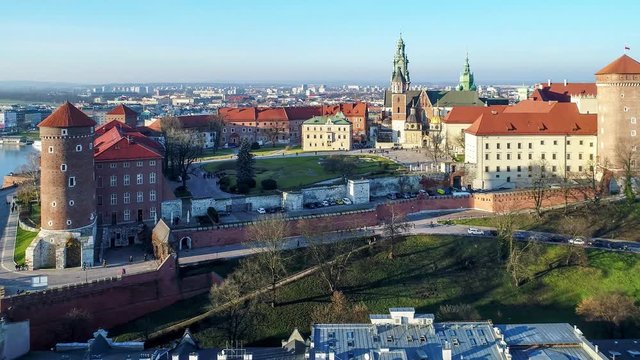 Royal Wawel Castle and Gothic Cathedral in Cracow, Poland, with Renaissance Sigismund Chapel with golden dome,  fortified walls, yard, park and tourists. Aerial 4K flyby video at sunset in winter.