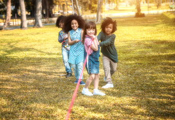 Children are happy to play tug at the park. Soft focus concept.