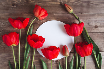 Row of red tulips on wooden background with space for message. Women's or Mother's Day background. Top view