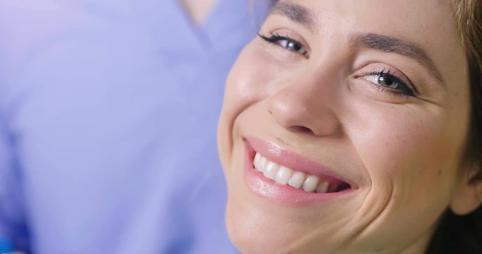 In a professional practice, a dentist checks the dentition of the patient, and she is happy with the visit, smiling, showing the perfect white teeth. Concept of: dentists, healthcare, perfect smile.