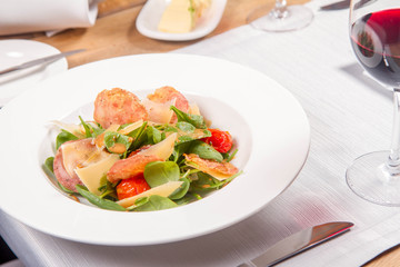 Baby spinach, dry sausage, matured cheese, roast tomatoes, thyme-balsamic vinaigrette salad served in a restaurant