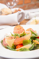 Baby spinach, dry sausage, matured cheese, roast tomatoes, thyme-balsamic vinaigrette salad served in a restaurant