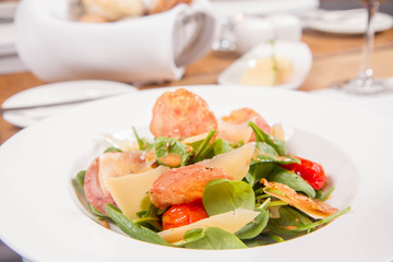 Baby spinach, dry sausage, matured cheese, roast tomatoes, thyme-balsamic vinaigrette salad served in a restaurant