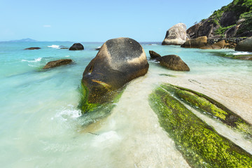 Image of sea waves splashing on rocks of tropical sandy beach