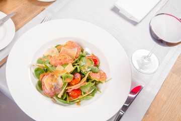 Baby spinach, dry sausage, matured cheese, roast tomatoes, thyme-balsamic vinaigrette salad served in a restaurant