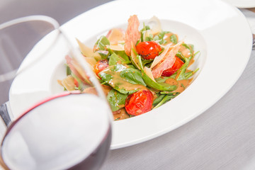 Baby spinach, dry sausage, matured cheese, roast tomatoes, thyme-balsamic vinaigrette salad served in a restaurant