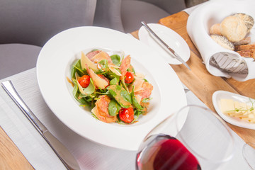 Baby spinach, dry sausage, matured cheese, roast tomatoes, thyme-balsamic vinaigrette salad served in a restaurant