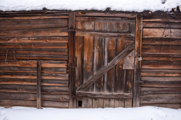 A general view at the wall and door with locked padlock of an old wooden house