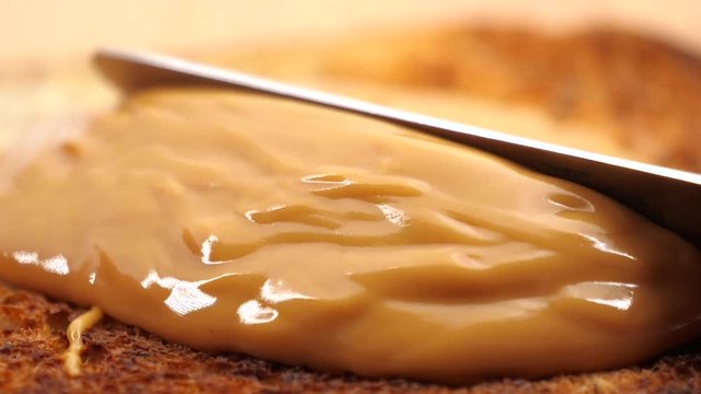 Slow motion Macro of spreading creamy peanut butter