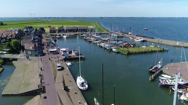 Aerial of Marken harbor panning camera drone to right showing recreational boats and the Markermeer in background the characteristic wooden houses of Marken are a popular tourist attraction 4k