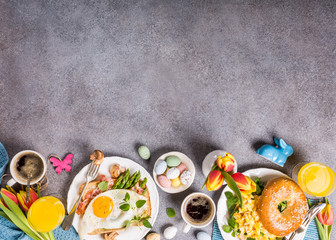 Fototapeta na wymiar Easter breakfast flat lay with scrambled eggs bagels, orange tulips, bread toast with fried egg and green asparagus, colored quail eggs and spring holidays decorations. Top view. Copy space.