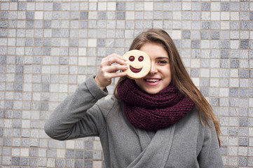 jolly girl with long hair keeping a cookie of the smiley form like a concept of happy life with...