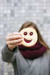 jolly girl with long hair keeping a cookie of the smiley form like a concept of happy life with...