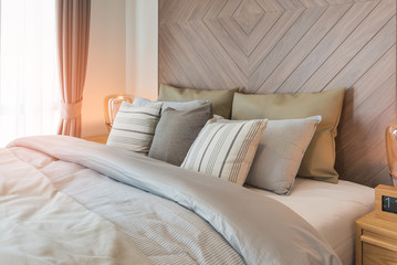 set of pillows on bed with wooden wall
