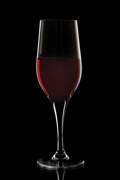 Transparent wine glass with red wine on black background, elegant image for use in design