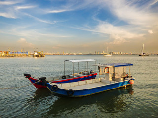 Fototapeta premium Speed boats at the Clan Jetties of Georgetown with a city view and a dramatic blue sky in the background - Penang, Malaysia