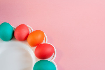 Easter background. Several painted eggs are lying on wavy white dish on pink paper background.