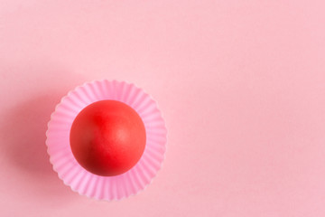 Easter background. One red egg in pink cupcakes mold on a pink background with copy space.