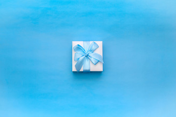 Gift box decorated with a satin ribbon on a blue background.