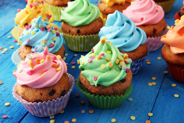 Tasty cupcakes on wooden background. Birthday cupcake in rainbow colors - Powered by Adobe