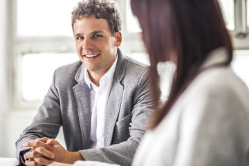 Young businessman looking at female colleague in office