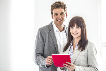 Portrait of smiling young business people with note pad in office