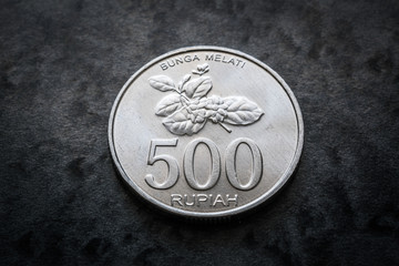 Currency of Indonesia, five hundred rupiah coin reverse with jasmine flower and coin value on black background